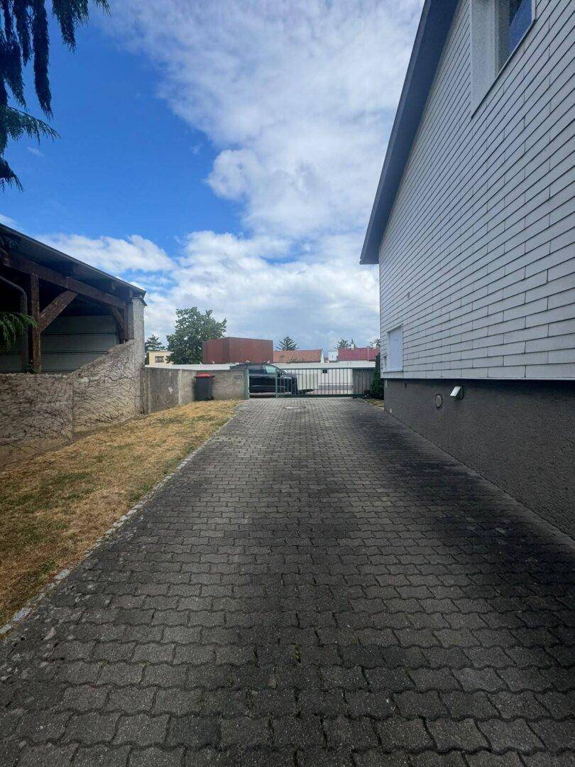 Lange gepflasterte Einfahrt führt zum hinteren Bereich des Grundstücks mit einem Tor.