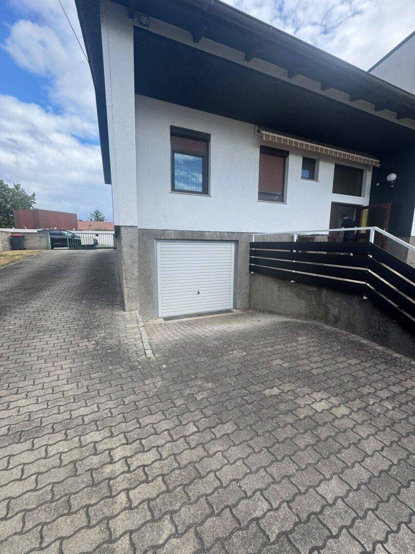 Vorderansicht des Hauses mit integrierter Garage und Treppe zum Eingangsbereich.