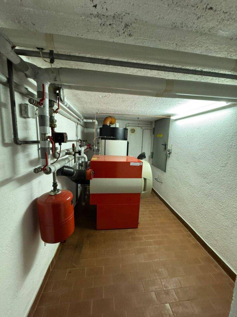 Heizungsraum im Keller mit einem modernen Heizkessel und sichtbaren Rohrleitungen.