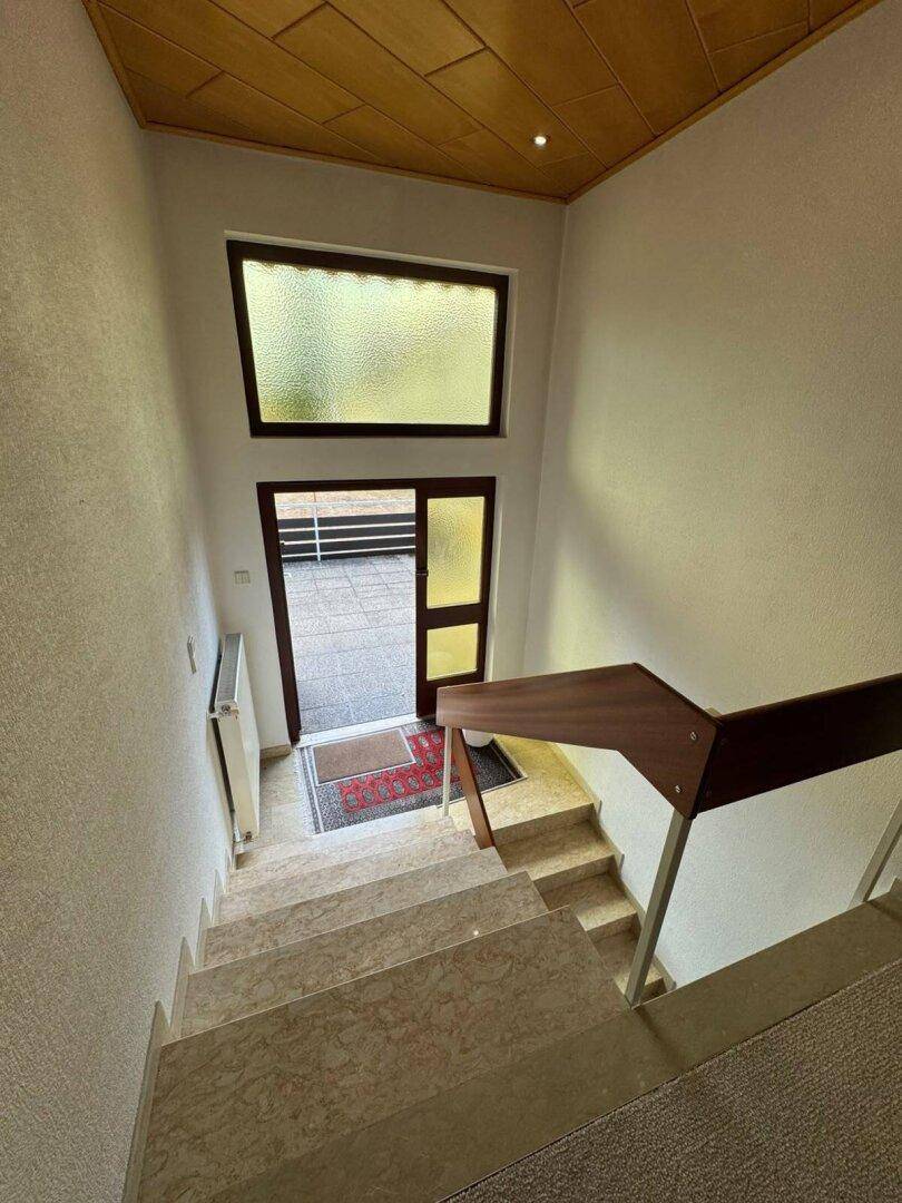 Blick von der Treppe im Eingangsbereich hinunter zum Hauseingang mit Marmorboden.