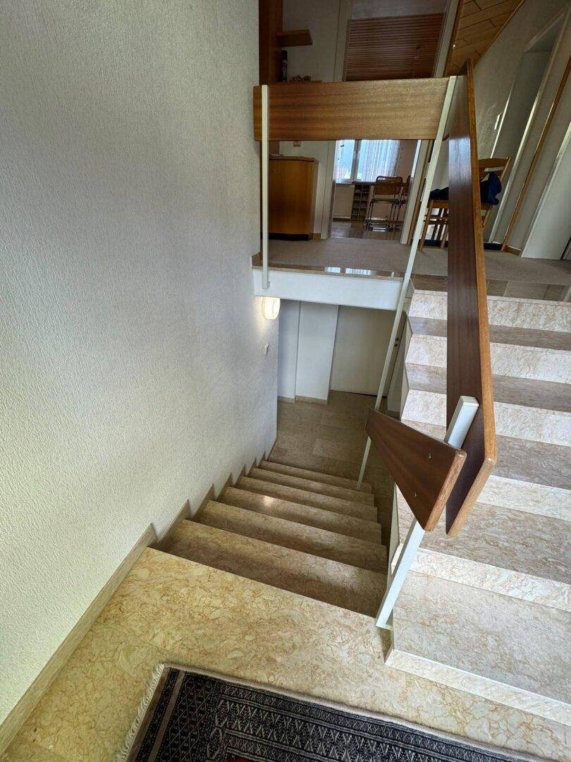 Treppenhaus mit Marmorstufen und Holzgeländer, das zu den verschiedenen Ebenen führt.