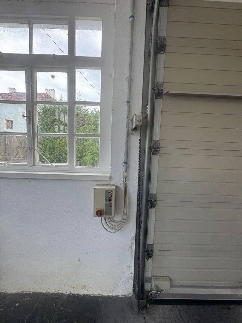 Detailansicht eines Fensters und einer Steuerungseinheit in der Garage, mit Blick nach draußen.