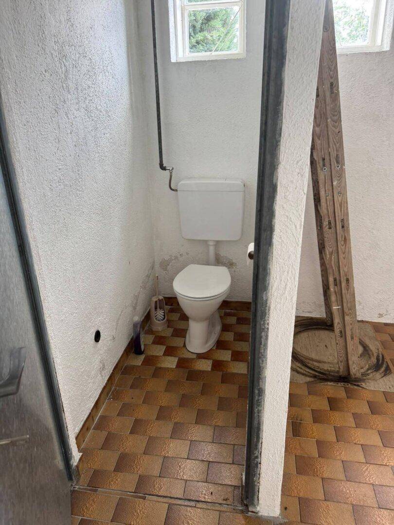 Kleiner Toilettenraum mit WC und braun-gemusterten Fliesen, einfach und funktional.