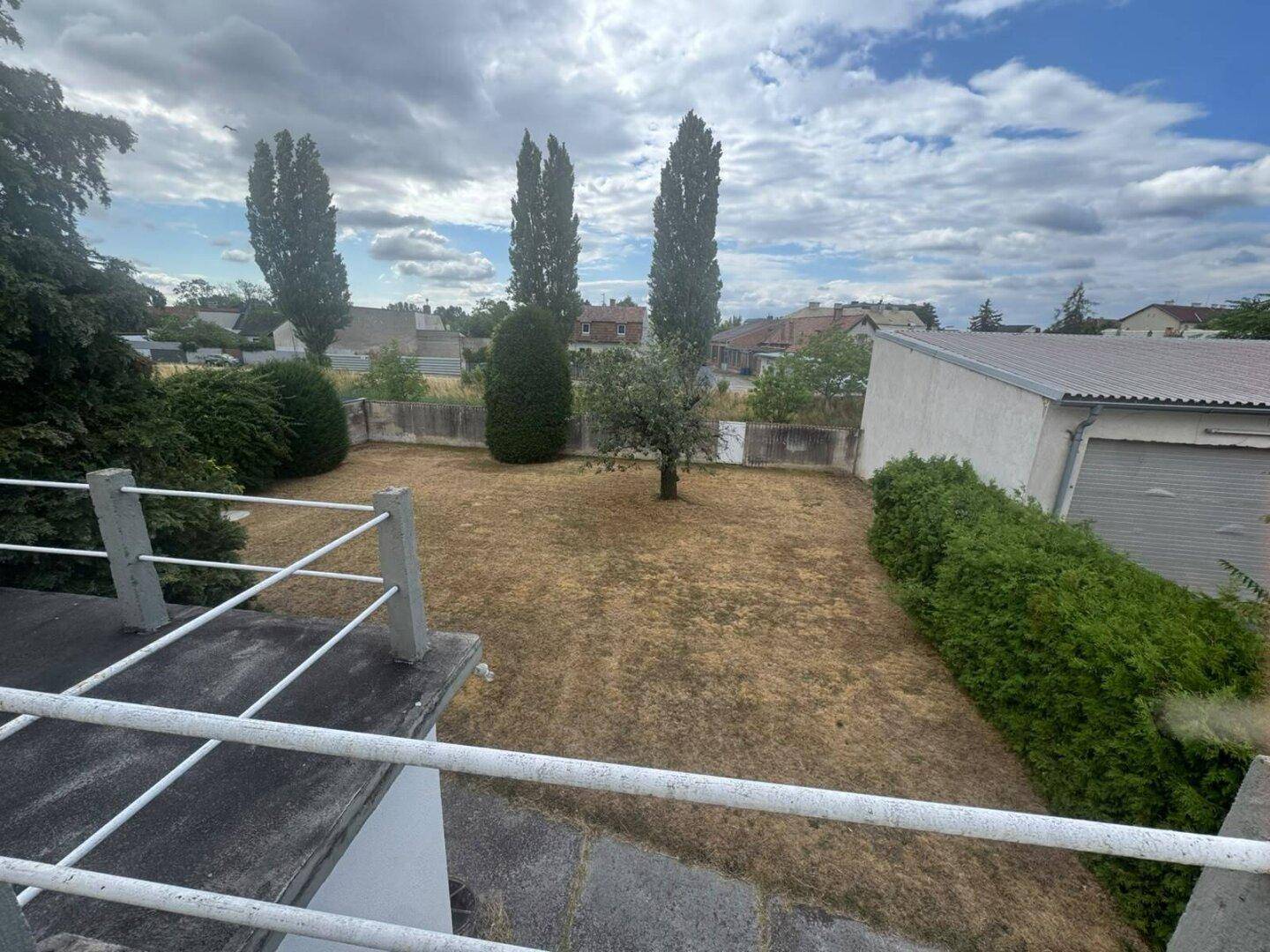 Weitläufiger Blick vom Balkon auf den Garten und die Nachbarschaft an einem sonnigen Tag.