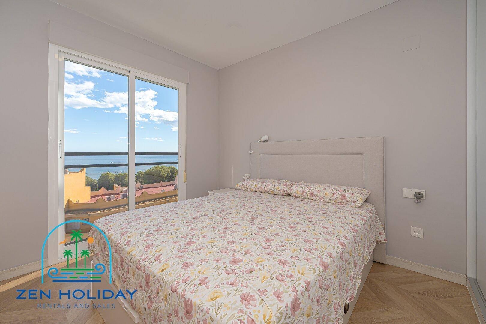 Hauptschlafzimmer mit Doppelbett und großen Fenstern, die einen weiten Blick auf das Meer bieten.