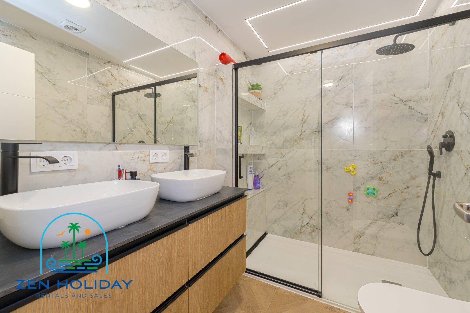 Elegantes Badezimmer mit Doppelwaschbecken, großem Spiegel und geräumiger begehbarer Dusche.