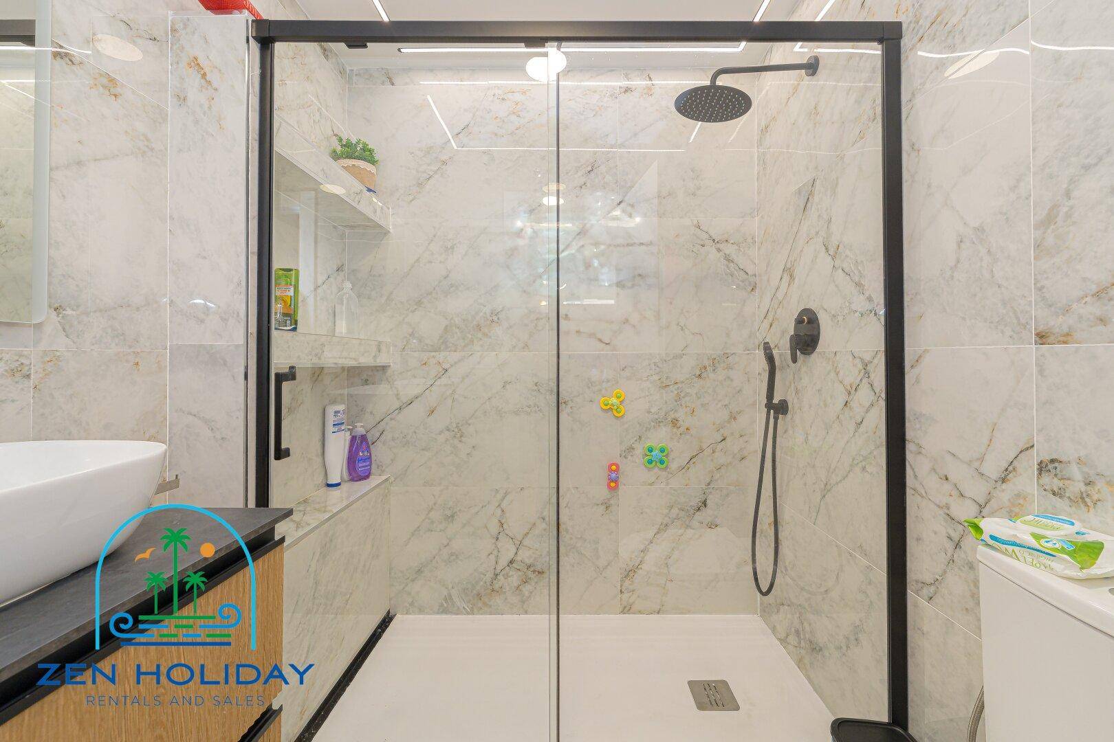 Modernes Badezimmer mit begehbarer Dusche und eleganten Marmorfliesen an den Wänden.