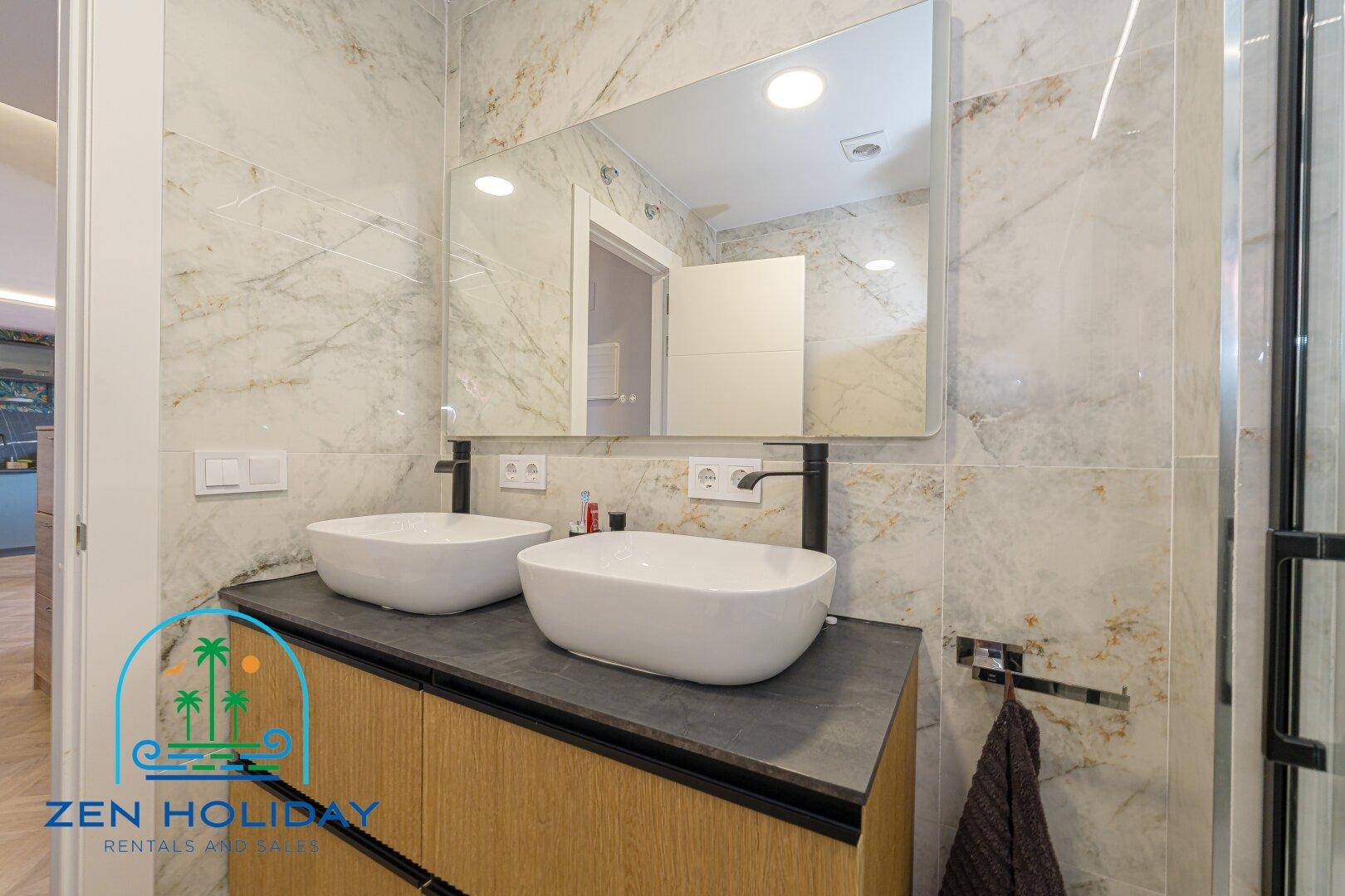 Badezimmer mit modernem Doppelwaschbecken und großem Wandspiegel über dem Waschtisch.