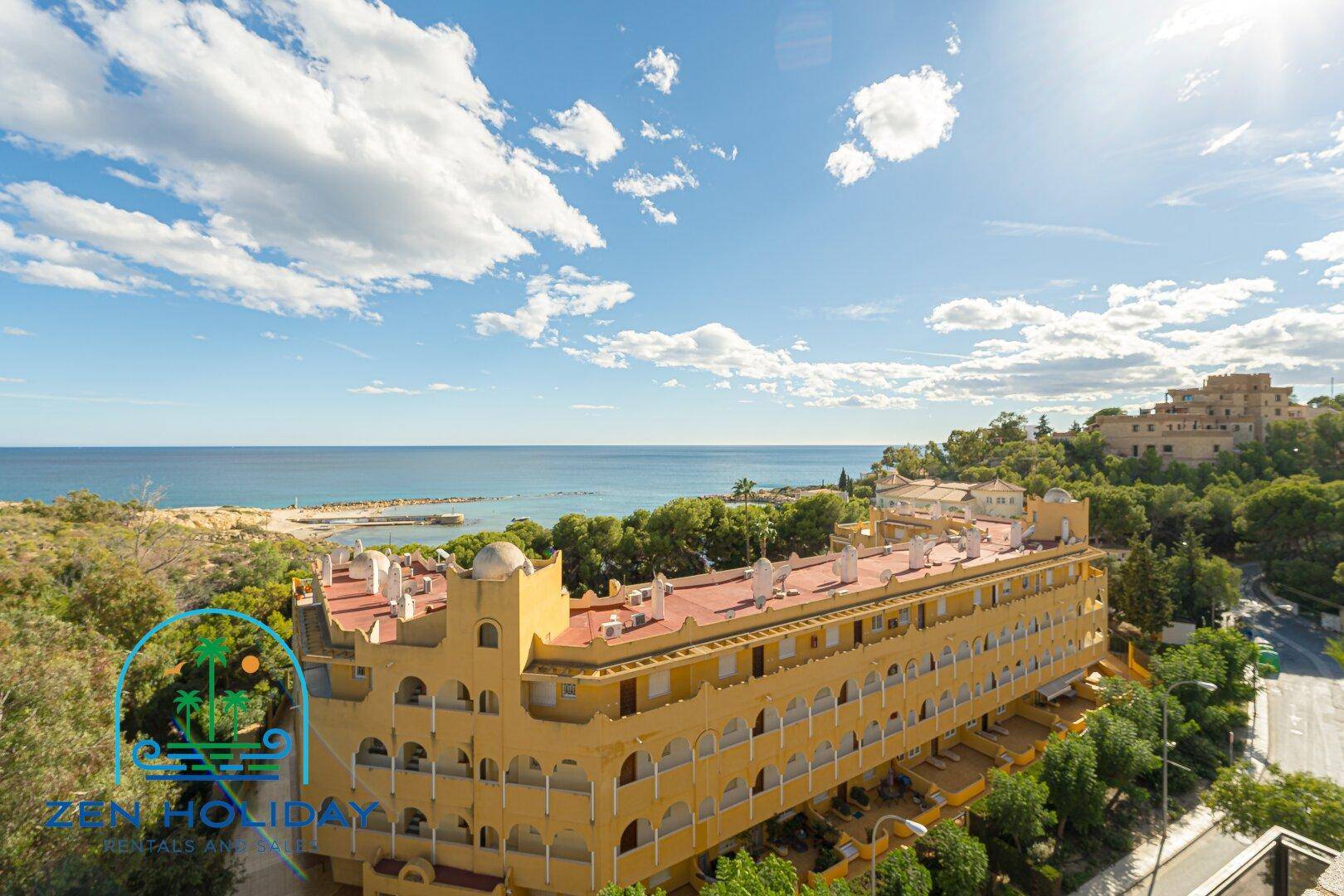 Panoramablick auf ein markantes gelbes Gebäude mit rotem Dach und das weite Meer im Hintergrund.