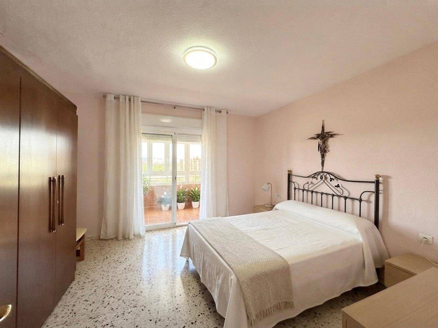 Geräumiges Schlafzimmer mit Doppelbett, großem Kleiderschrank und direktem Zugang zum Balkon.