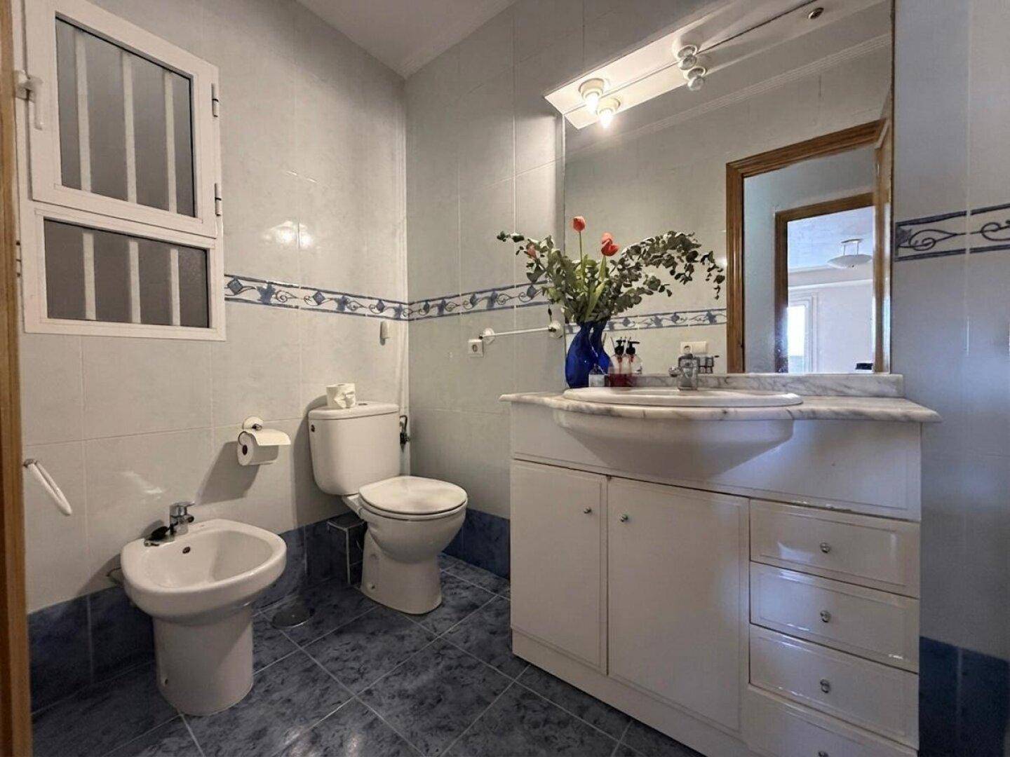 Badezimmer mit blauen und weißen Fliesen, Waschtisch, Toilette und Bidet.
