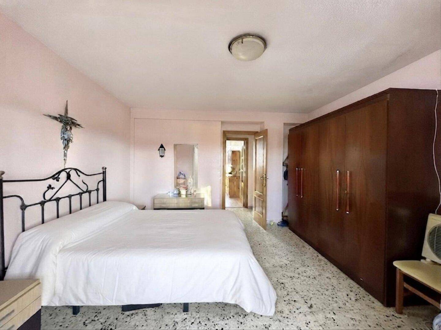 Schlafzimmer mit großem Holzschrank und Terrazzoboden, bietet viel Stauraum.