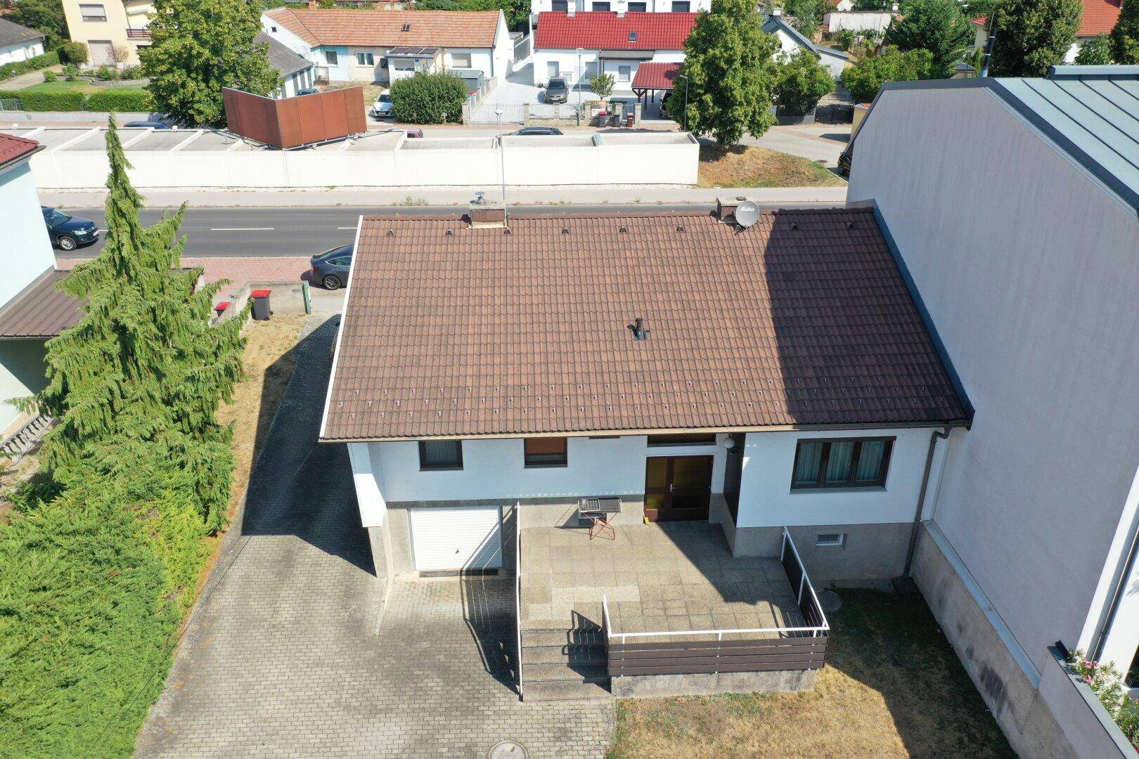 Luftaufnahme der Hausfront mit Einfahrt und angrenzender Straße in einer Wohngegend.