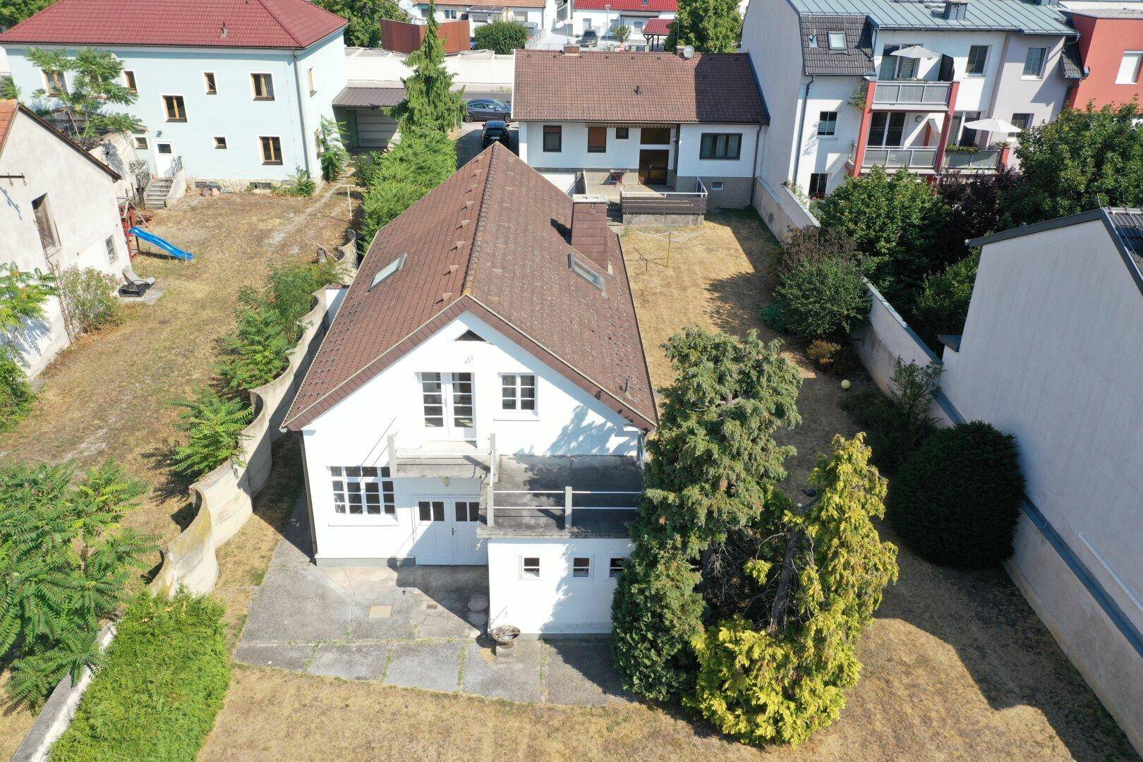 Luftaufnahme der Rückseite des Hauses mit kleiner Terrasse und trockenem Gartenbereich.