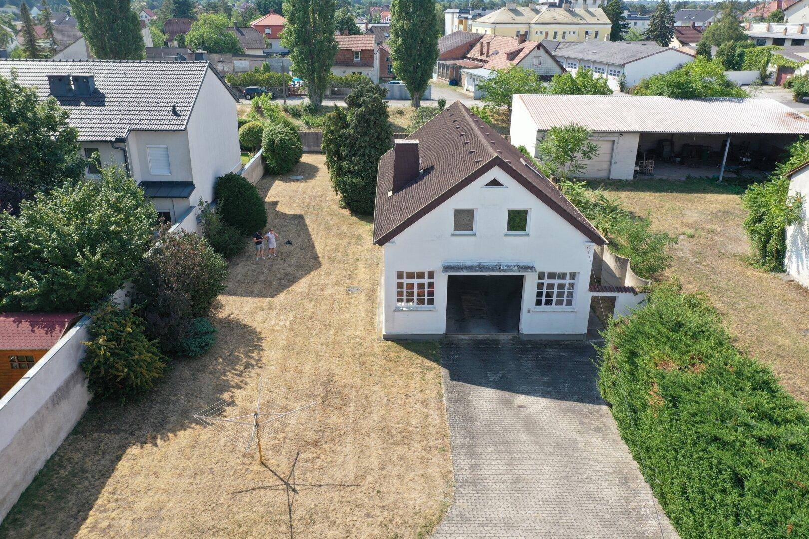 Luftaufnahme der Hausfront mit gepflasterter Einfahrt und grüner Hecke.