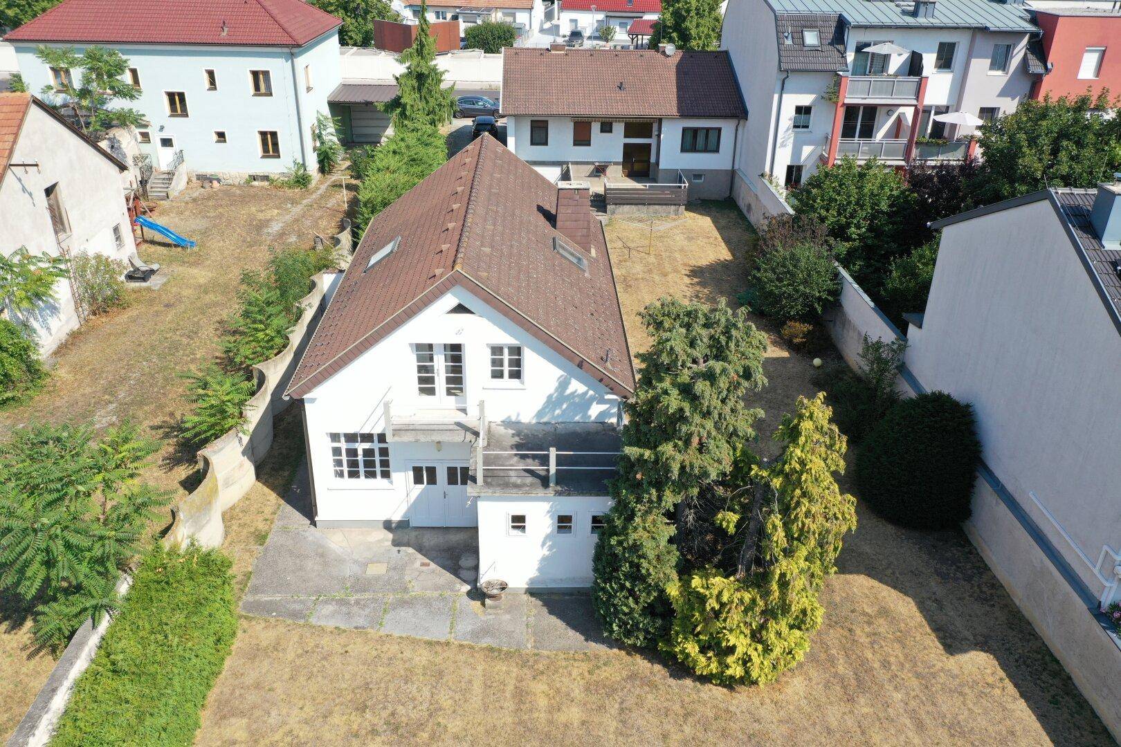 Luftaufnahme der Rückseite des Hauses mit kleiner Terrasse und trockenem Gartenbereich.
