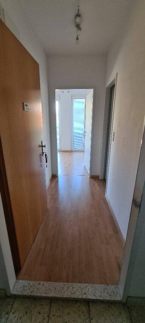 Heller Flur mit Holzboden und einer Holztür, die zu weiteren Räumen führt.