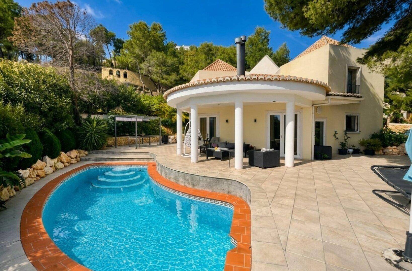 Villa mit großem Poolbereich, überdachter Terrasse und üppiger mediterraner Vegetation.