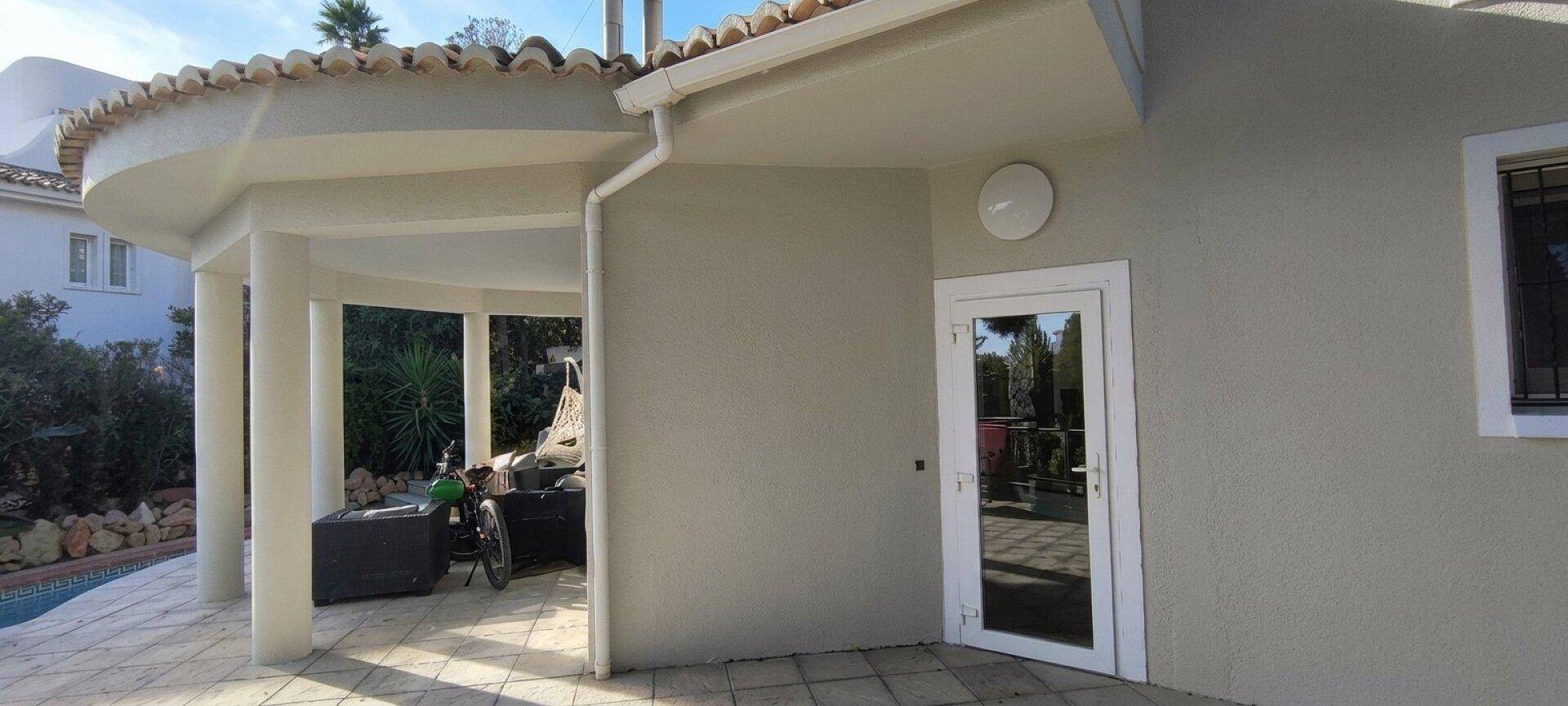 Überdachter Terrassenbereich mit Zugang zum Haus und Blick auf den Pool.