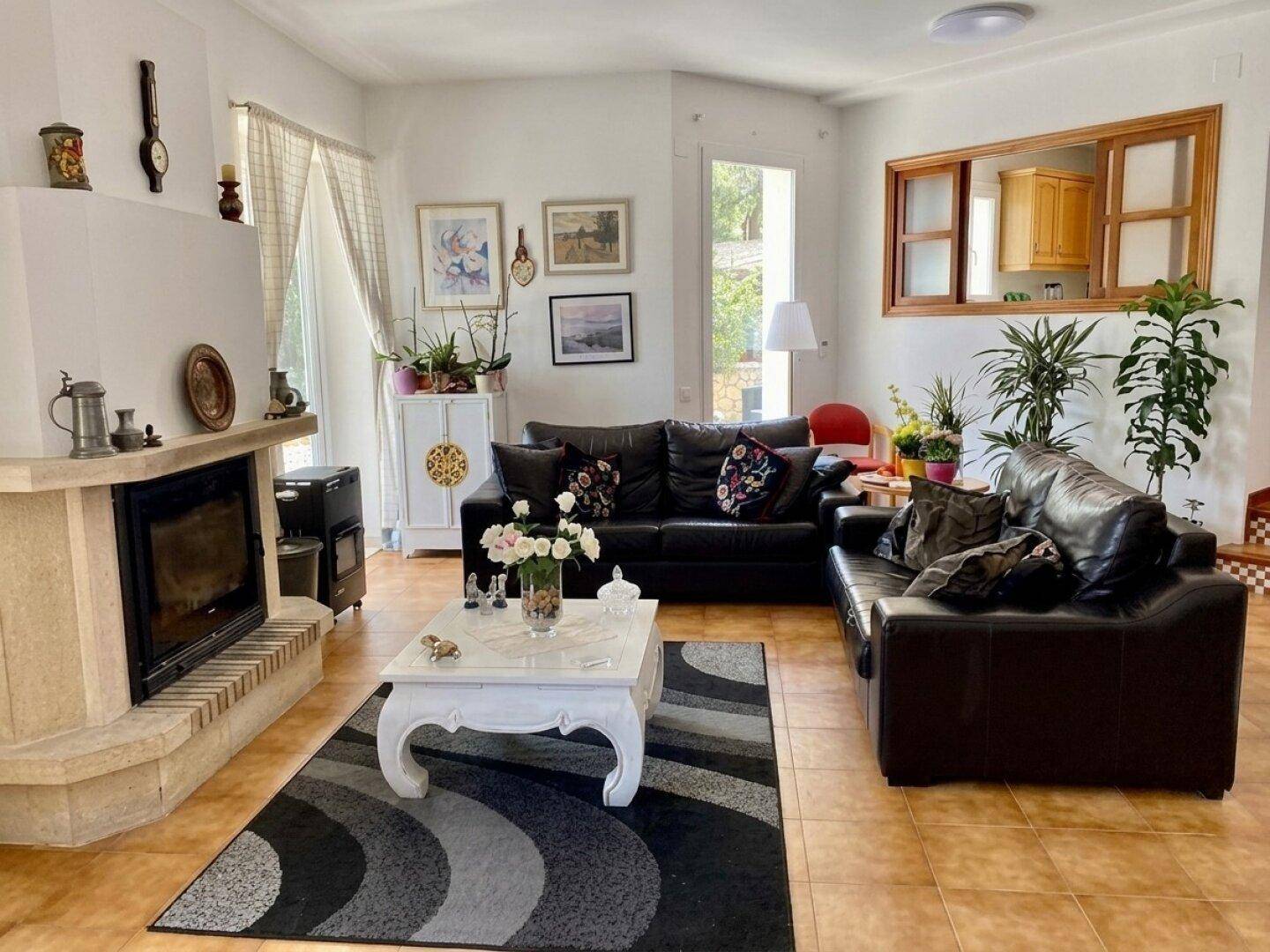 Gemütliches Wohnzimmer mit Kamin, Ledersofas und Terrakotta-Fliesenboden.