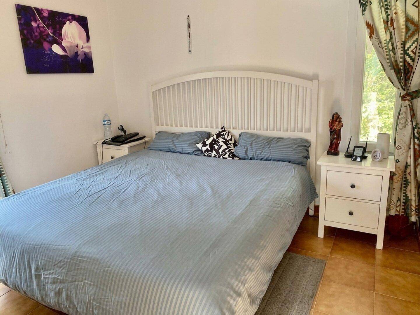 Schlafzimmer mit Doppelbett, Nachttischen und Terrakotta-Fliesenboden.