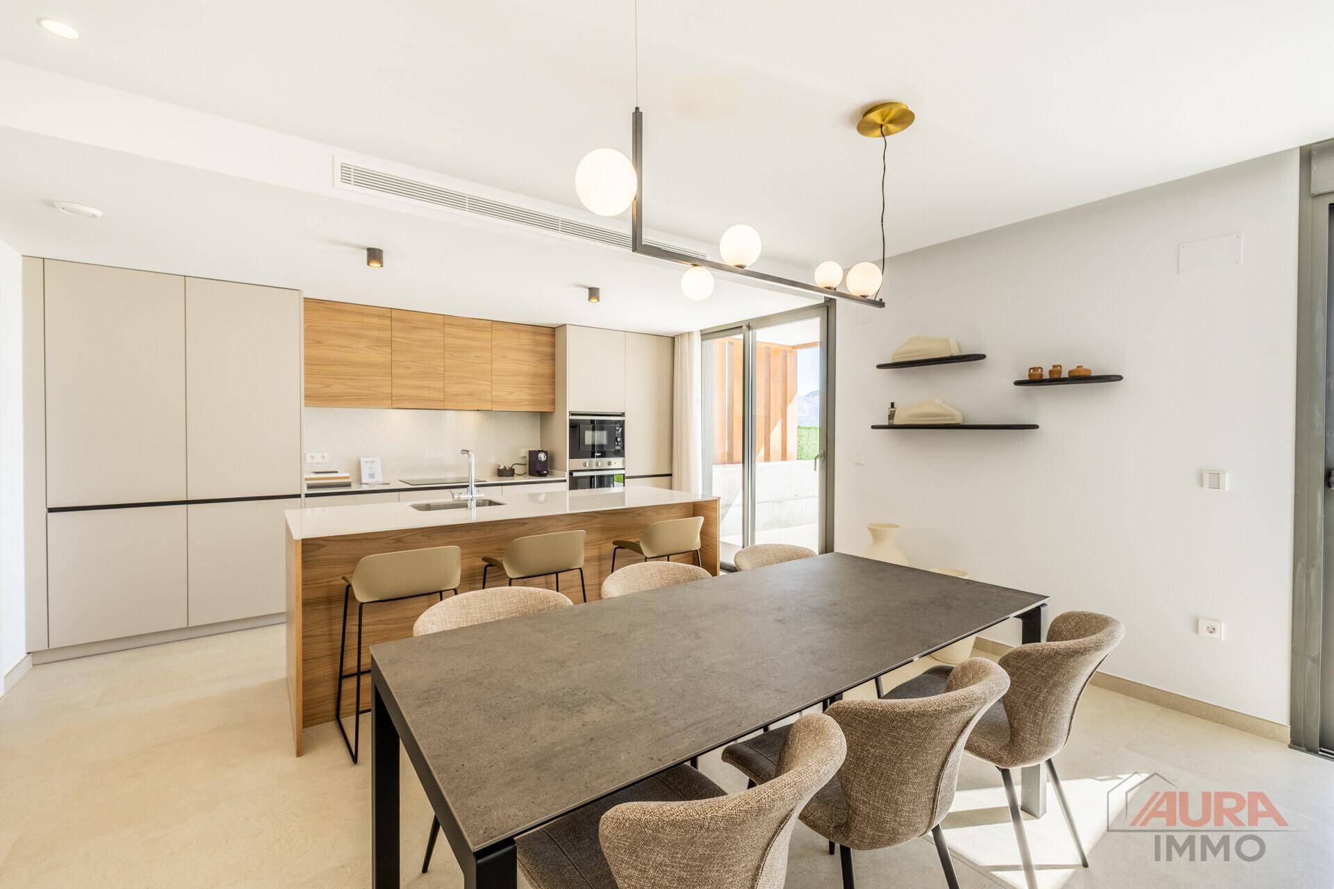 Moderne Küche mit Kochinsel, Essbereich und integrierten Geräten in hellem Design.