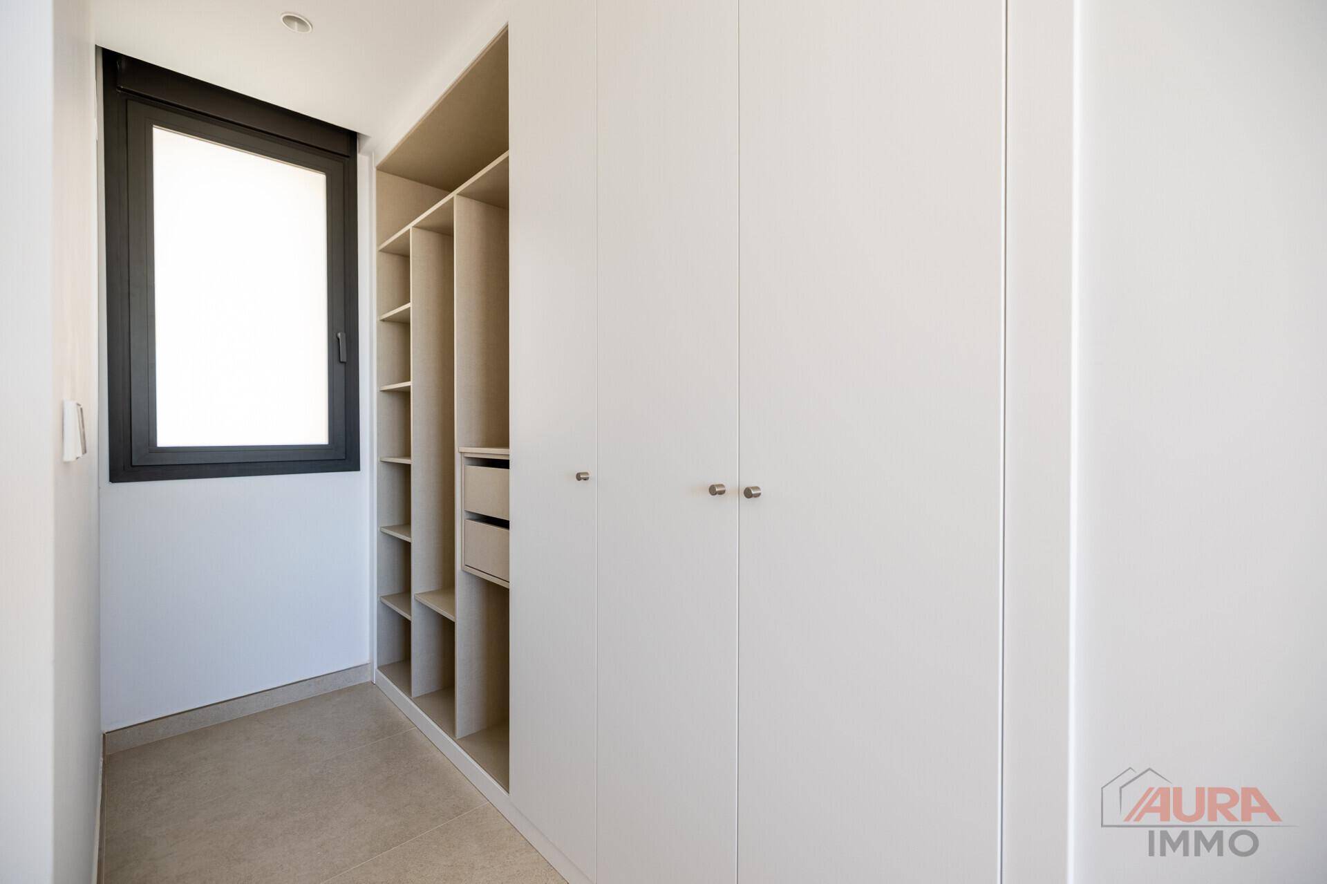 Heller begehbarer Kleiderschrank mit integrierten Regalen und Fenster.