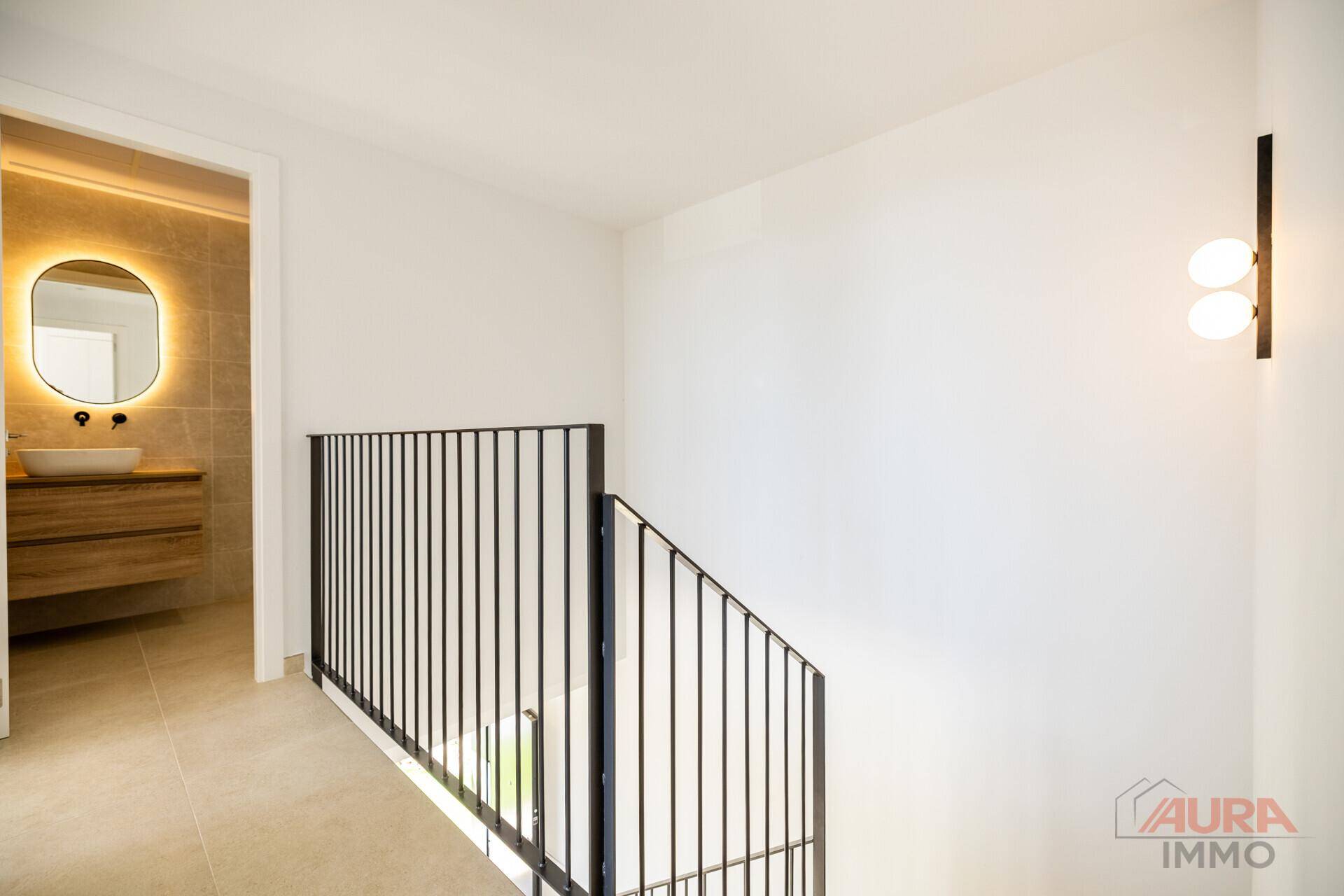 Heller Flur mit modernem Treppengeländer und Blick in ein stilvolles Badezimmer.