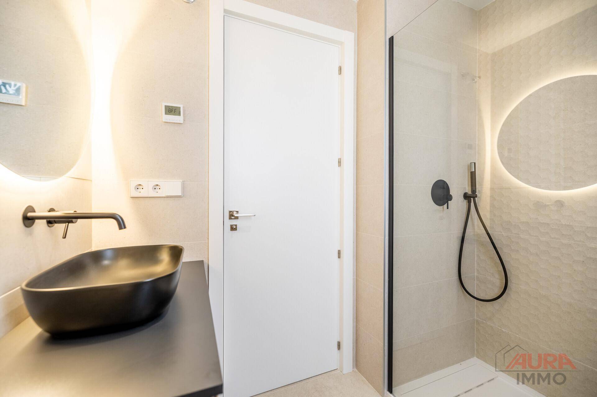 Stilvolles Badezimmer mit schwarzem Waschbecken, beleuchtetem Spiegel und begehbarer Dusche.