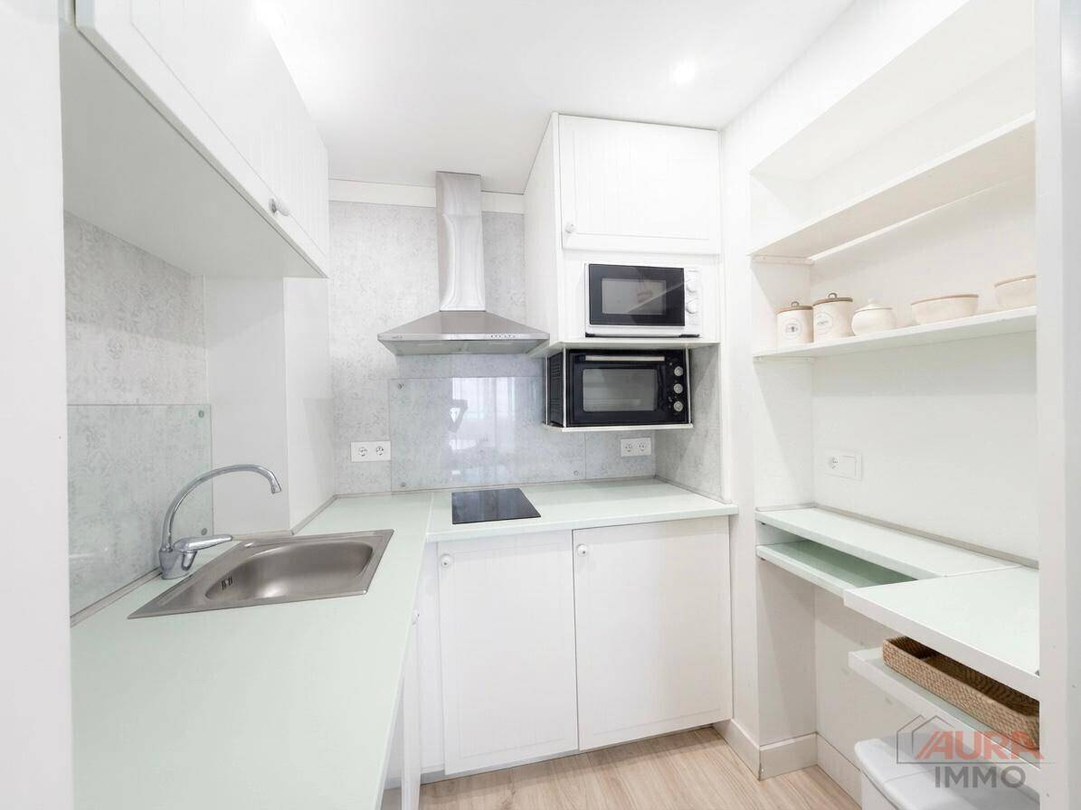 Kompakte, moderne Küche mit weißen Schränken, Induktionskochfeld und integrierten Geräten.