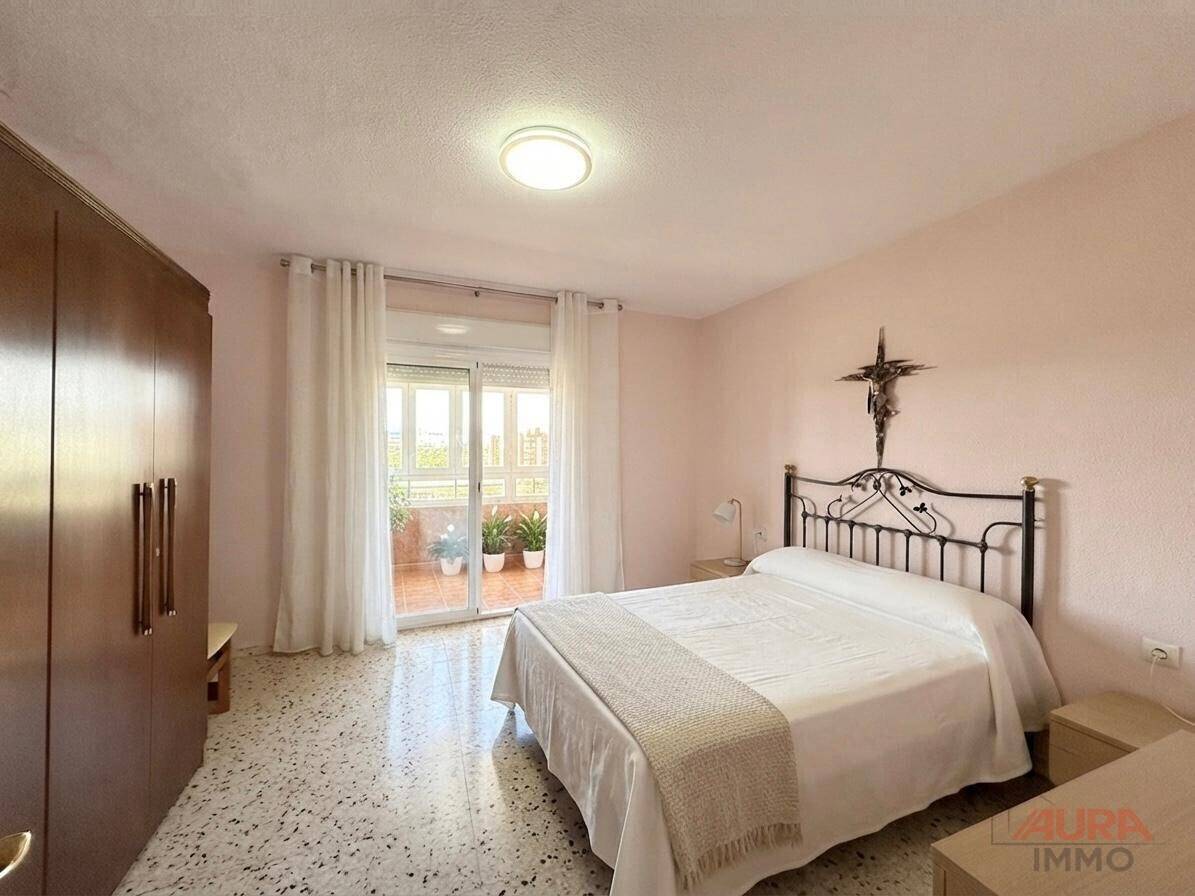 Helles Schlafzimmer mit Doppelbett, großem Kleiderschrank und Zugang zu einem Balkon.