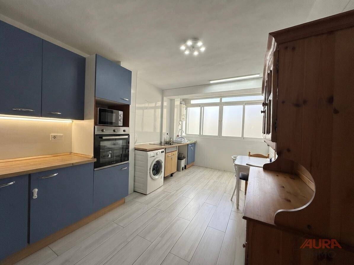 Moderne Küche mit blauen Schränken, integrierten Geräten und viel Arbeitsfläche am Fenster.