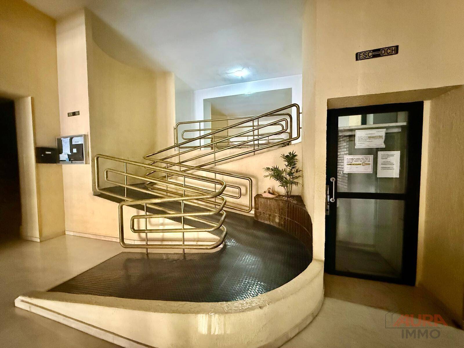 Eingangsbereich mit einer Rampe und Treppe, ausgestattet mit Metallgeländern für den Zugang.