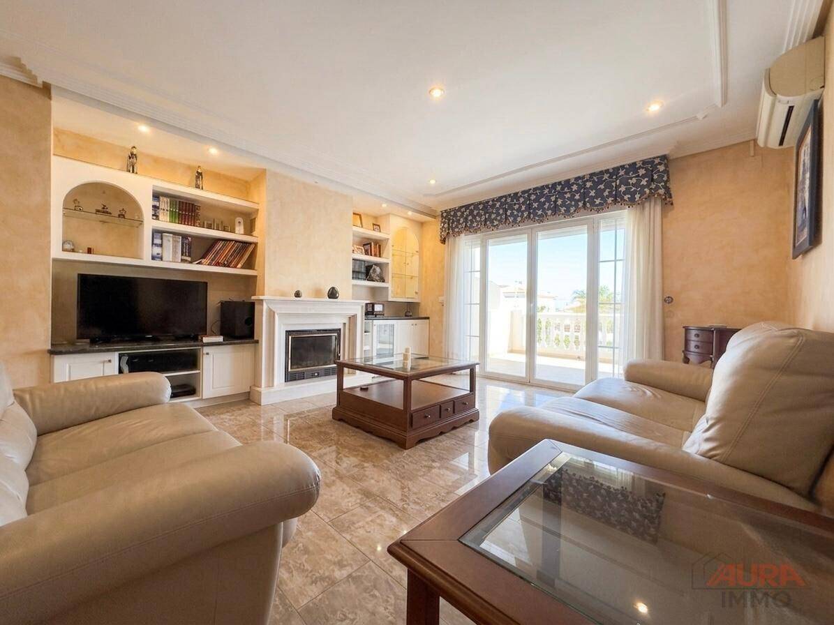 Gemütliches Wohnzimmer mit Kamin, bequemen Sofas und Zugang zu einem Balkon.