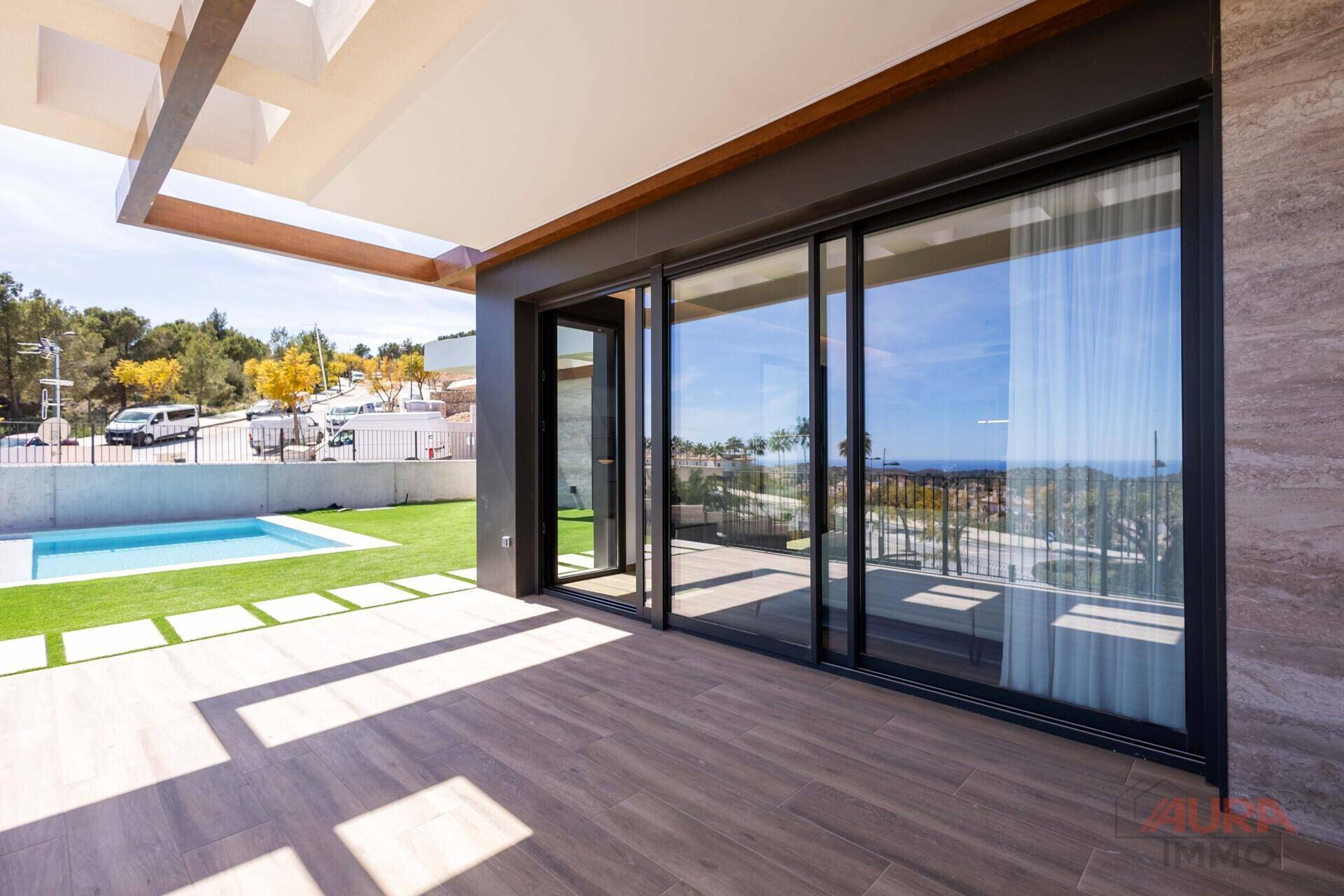 Große Terrasse mit Pool, Kunstrasenfläche und Zugang zum Innenbereich durch Schiebetüren.