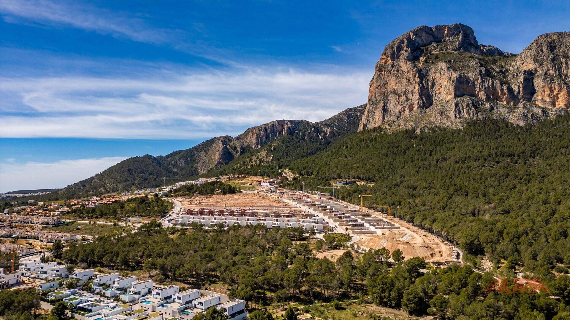 Weitläufige Baustelle einer neuen Wohnanlage in bergiger Landschaft mit Meerblick.