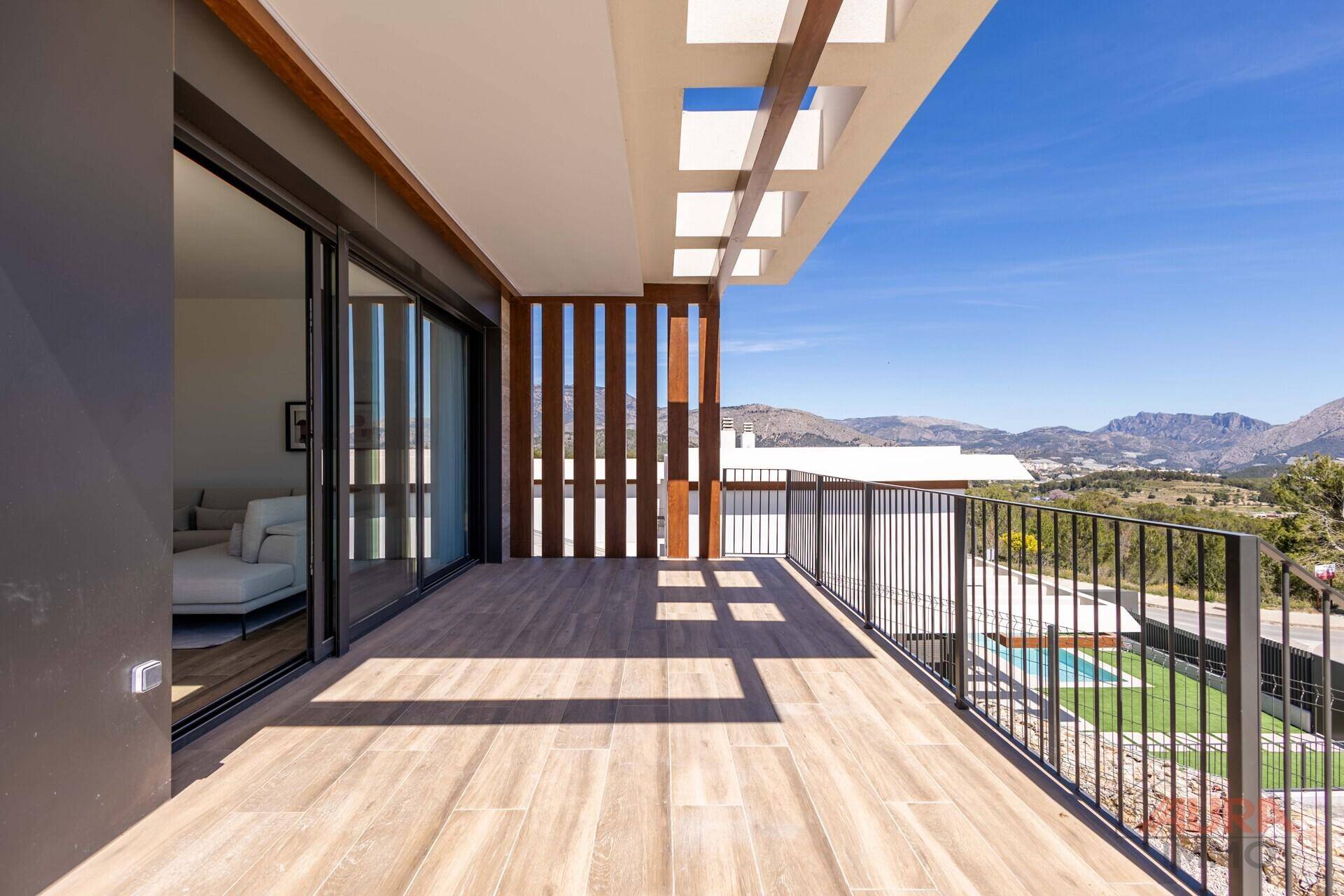 Geräumiger Balkon mit Holzelementen, Metallgeländer und weitem Blick auf Berge und Meer.