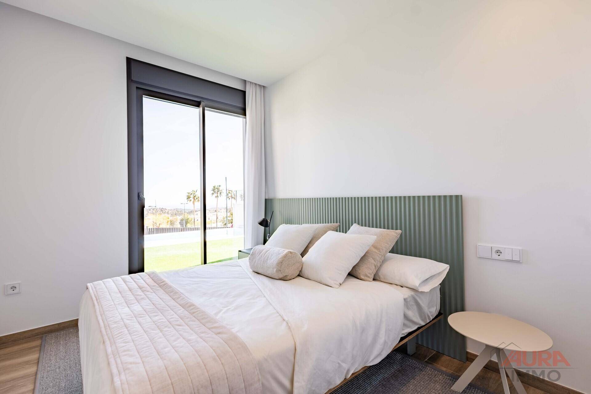 Freundliches Schlafzimmer mit modernem Kopfteil und großem Fenster mit Blick ins Grüne.