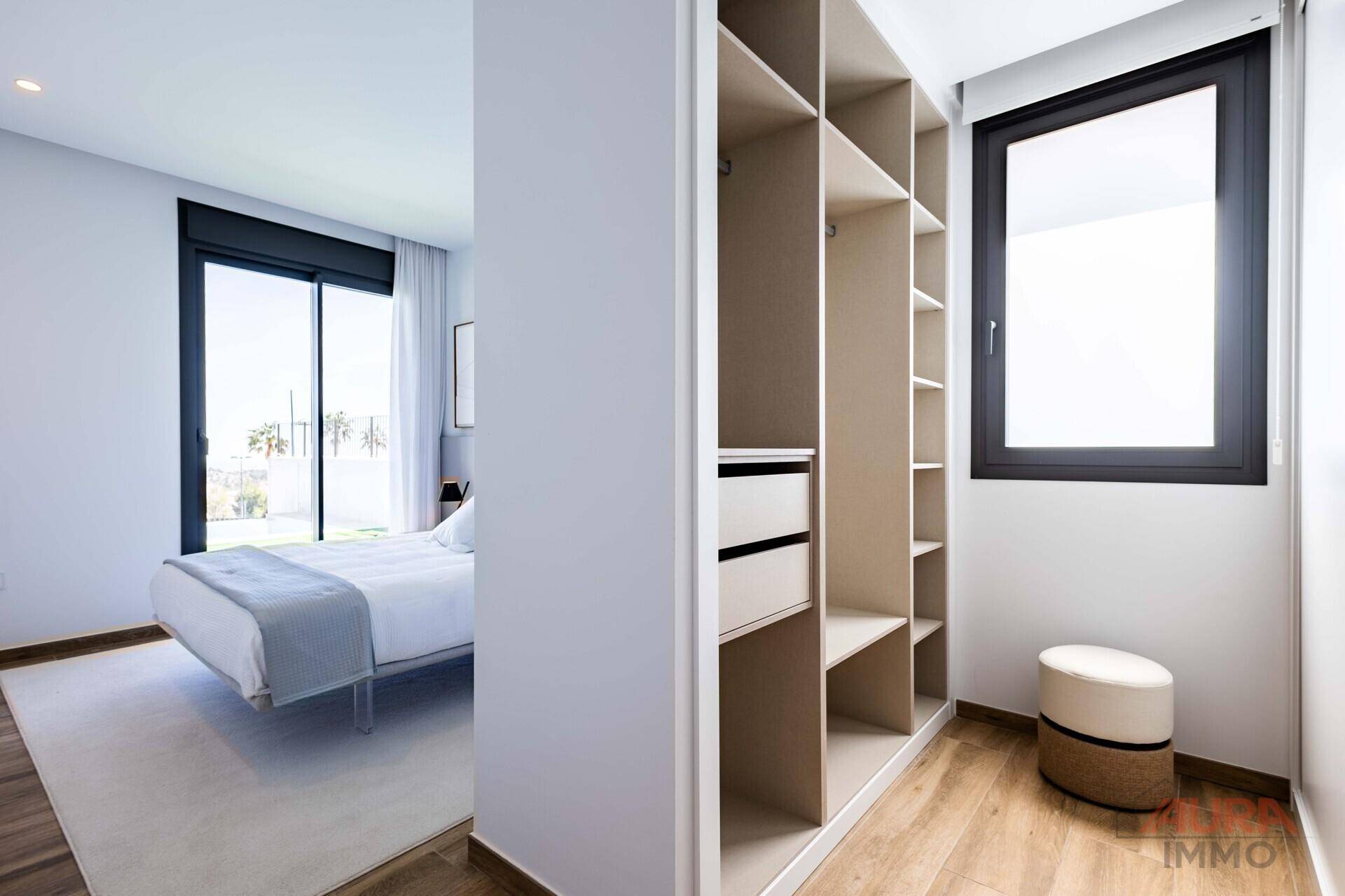Begehbarer Kleiderschrank mit Fenster und direktem Zugang zum hellen Schlafzimmer.