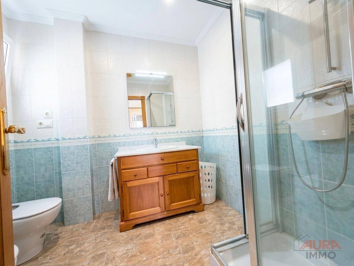 Funktionales Badezimmer mit Duschkabine, Einzelwaschbecken und hellblauen Wandfliesen.