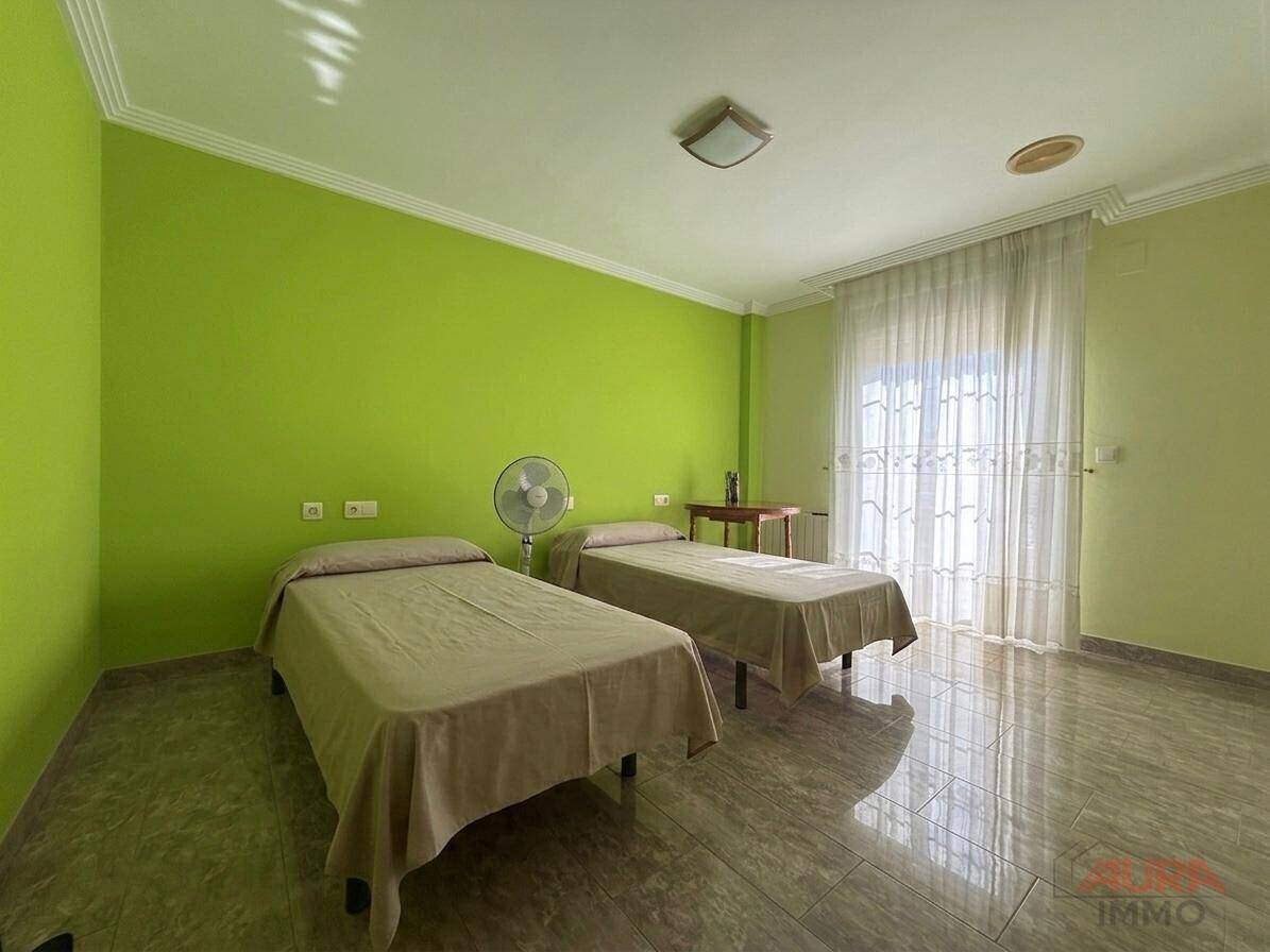 Geräumiges Schlafzimmer mit zwei Einzelbetten, grünen Wänden und großem Fenster für viel Licht.