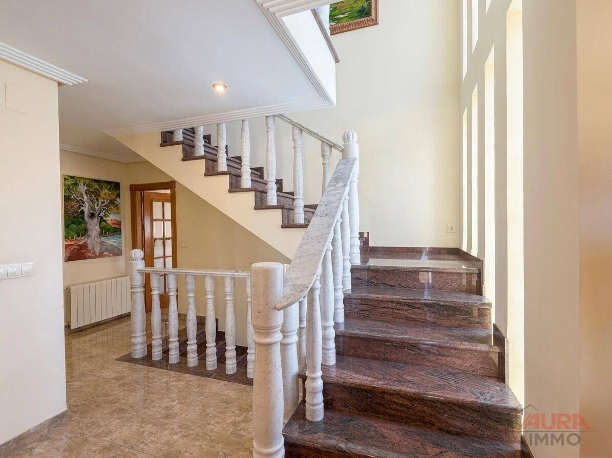 Elegante Treppe mit Marmorstufen und weißem Geländer, die verschiedene Etagen des Hauses verbindet.