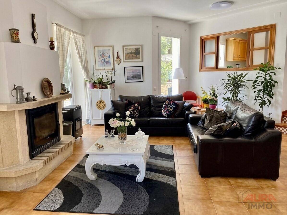 Gemütliches Wohnzimmer mit Kamin, Ledersofas und rustikalen Fliesenböden.