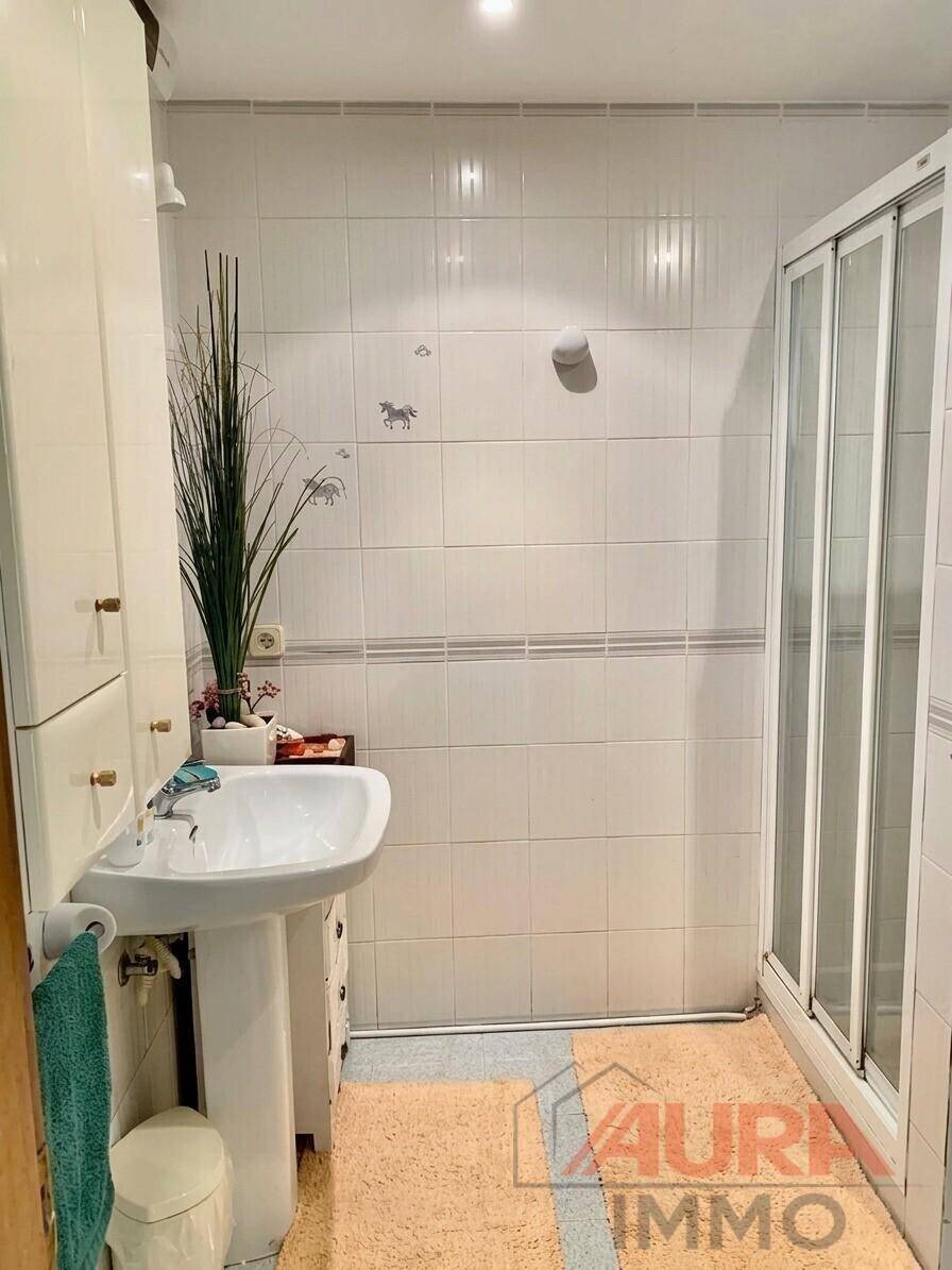 Funktionales Badezimmer mit Duschkabine, Waschbecken und weißen Fliesen.