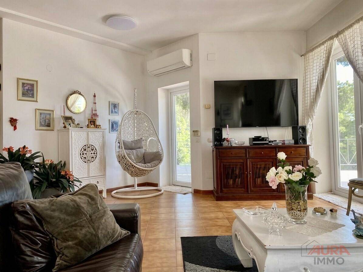 Helles Wohnzimmer mit Klimaanlage, Fernseher und Zugang zur Terrasse.