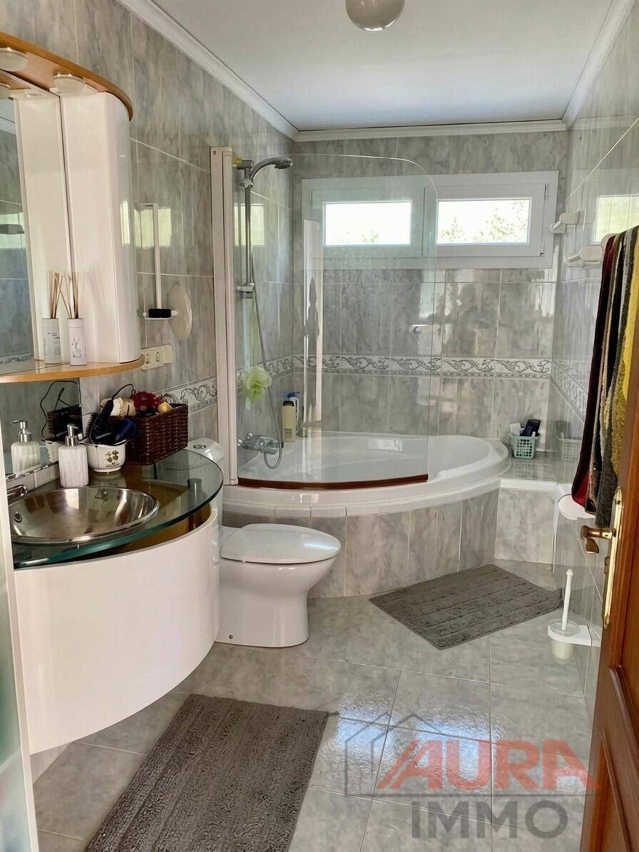 Helles Badezimmer mit Eckbadewanne, Dusche und modernen grauen Fliesen.