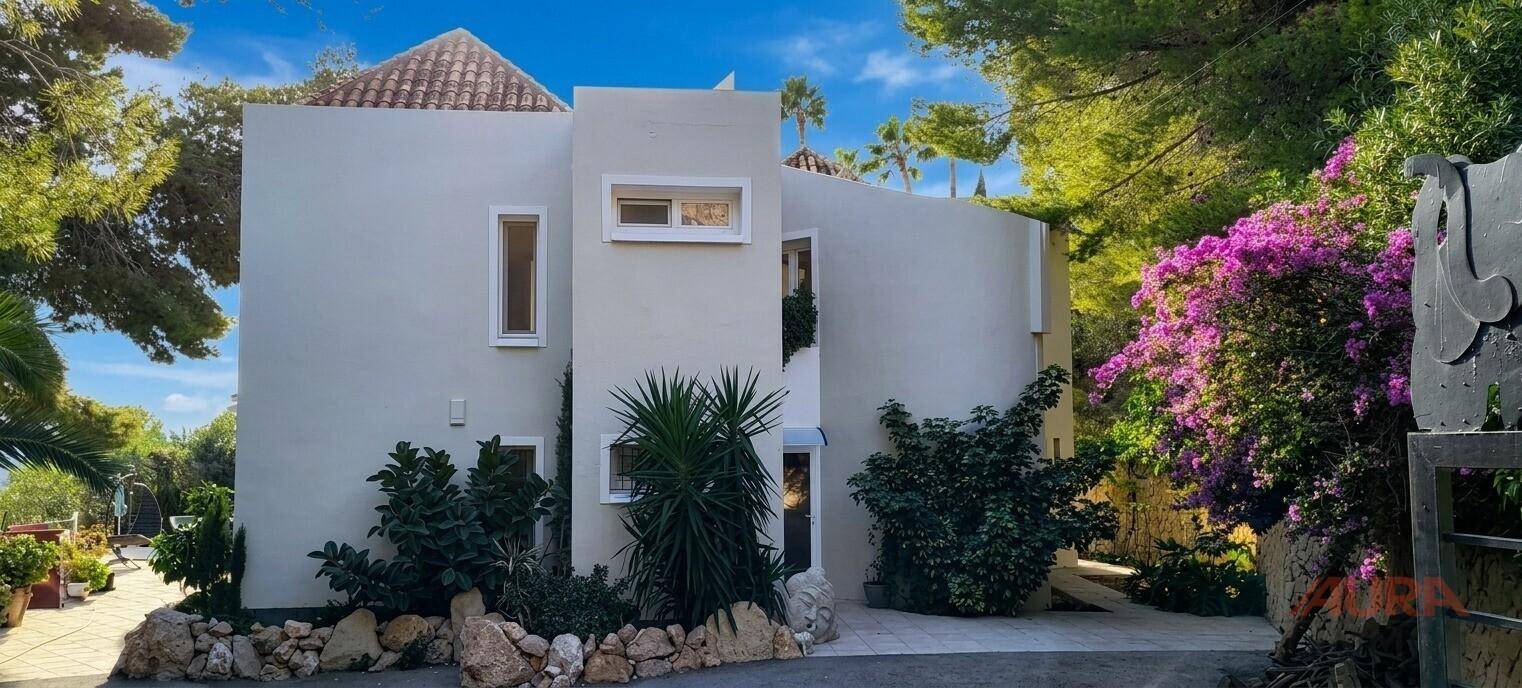 Moderne Fassade der Villa mit weißen Wänden und üppiger mediterraner Bepflanzung.