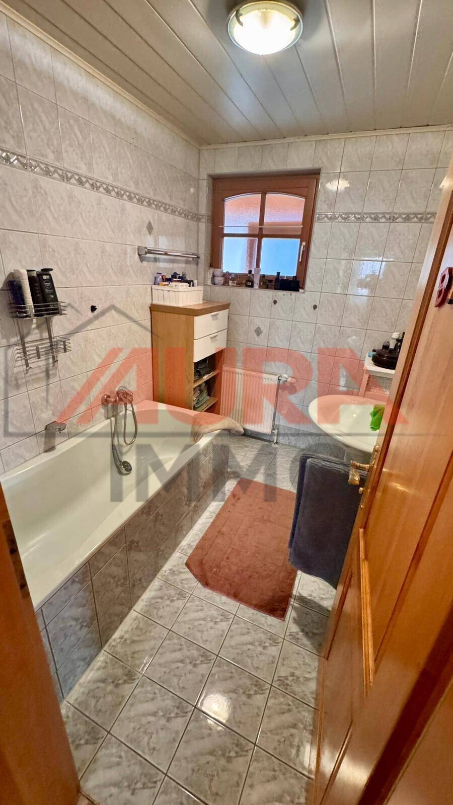 Helles Badezimmer mit Badewanne, Waschbecken und Fenster, für entspannende Momente.