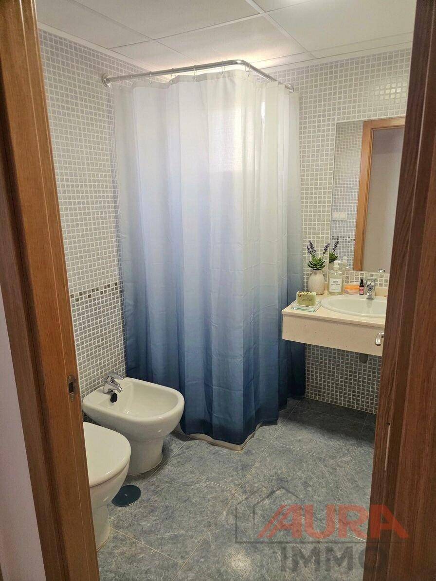 Badezimmer mit Dusche, Bidet und Waschbecken, ausgestattet mit hellblauen Mosaikfliesen.