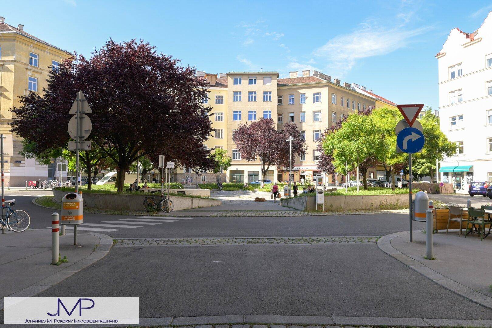 Panoramablick auf eine städtische Wohngegend mit gepflegten Gebäuden, Bäumen und einer Kreuzung.